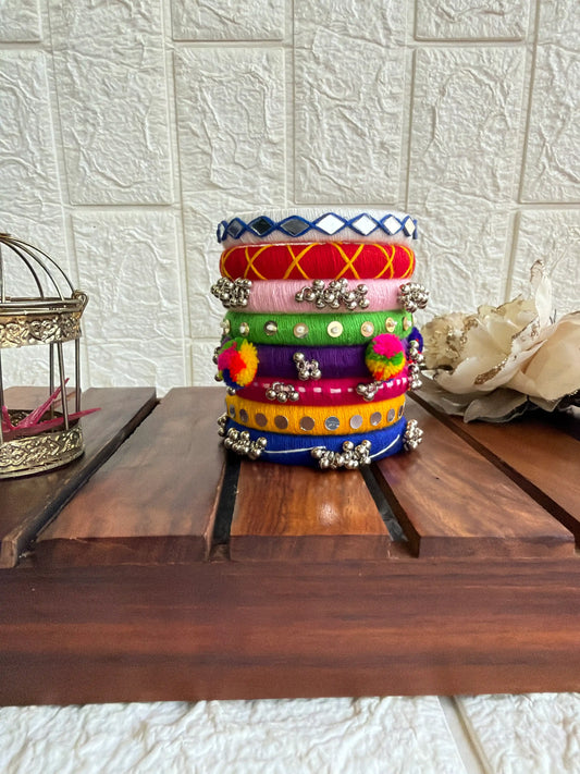 Aadhya Bangles — Multicolor thread bangles with mirror work, silver bells, kundan stones, silver charm ghungroo, parrot motifs, cowrie shells.